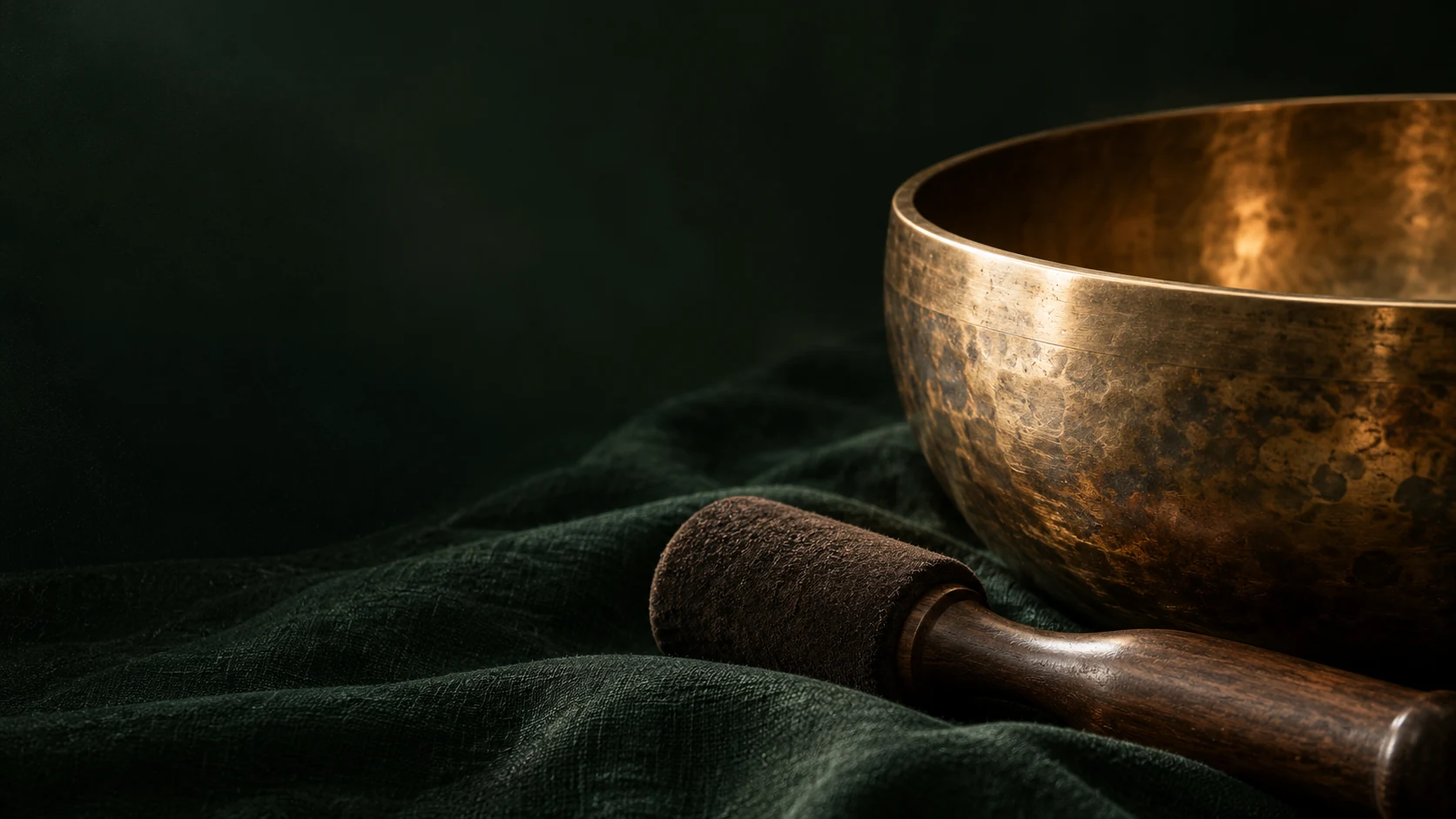 Un bol tibétain en bronze et son maillet dans une lumière douce